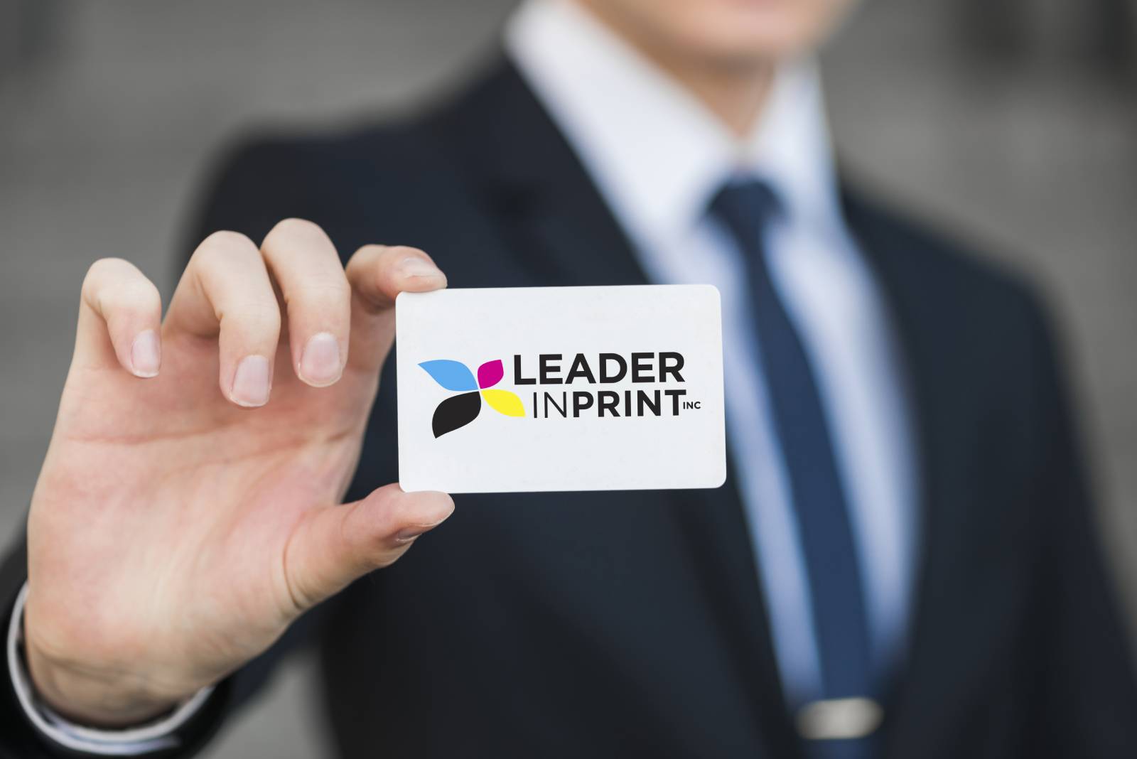 man in a suit holding a leader in print business card